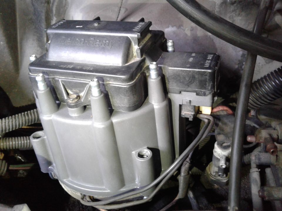 Gray Delco-Remy ignition distributor cap with black lettering and four visible spark plug wire terminals.