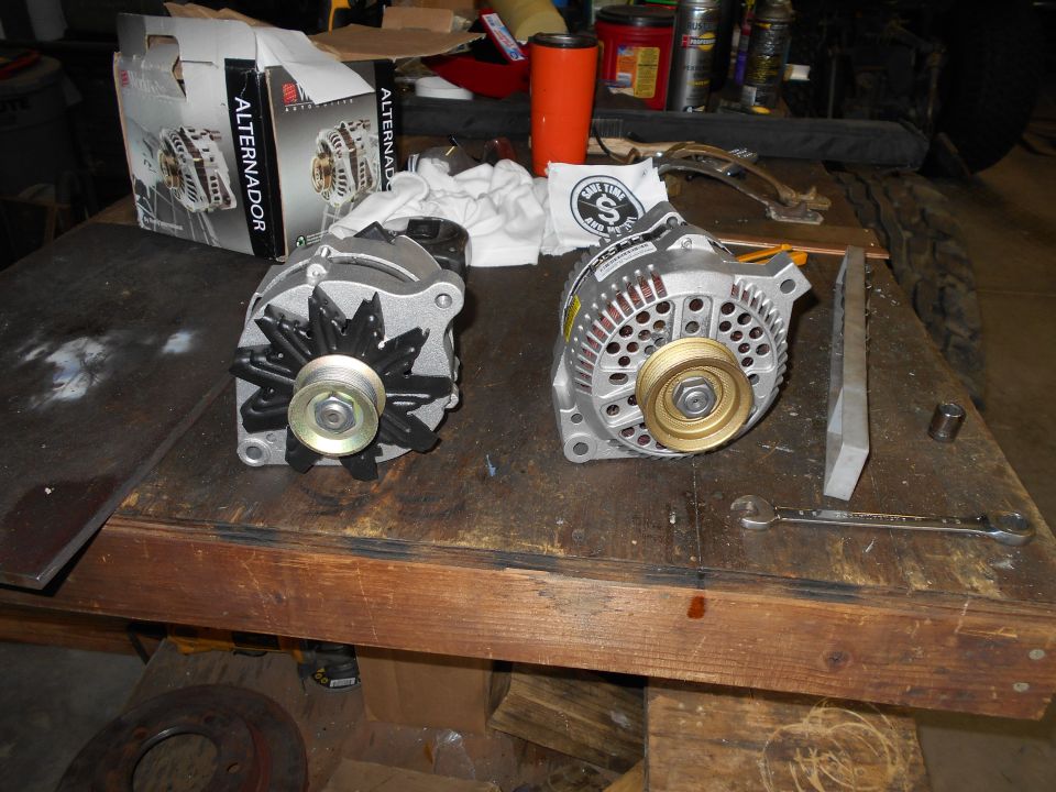Two automotive alternators on a workbench, one in a box.