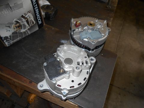 1992 Ford Bronco - Two silver alternators are displayed on a dark, textured surface. A cardboard box with an illustration of an alternator and the word "ALTER…