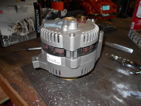 1992 Ford Bronco - A remanufactured alternator is shown on a workbench next to a box labeled "Alternador". The alternator has a label with the part number "27…