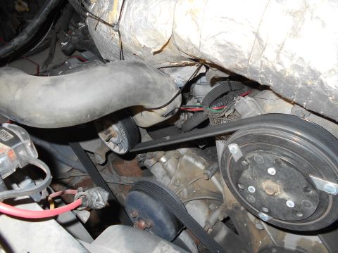 1992 Ford Bronco - A close-up view of the engine bay of a 1992 Ford Bronco, focusing on the serpentine belt system and a large rubber hose. The image shows va…