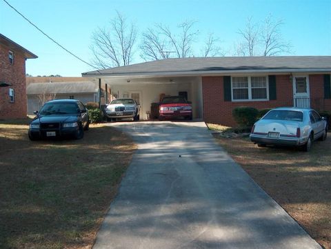 2001 Ford Crown Victoria - Four vehicles are parked in and around the driveway of a brick house.