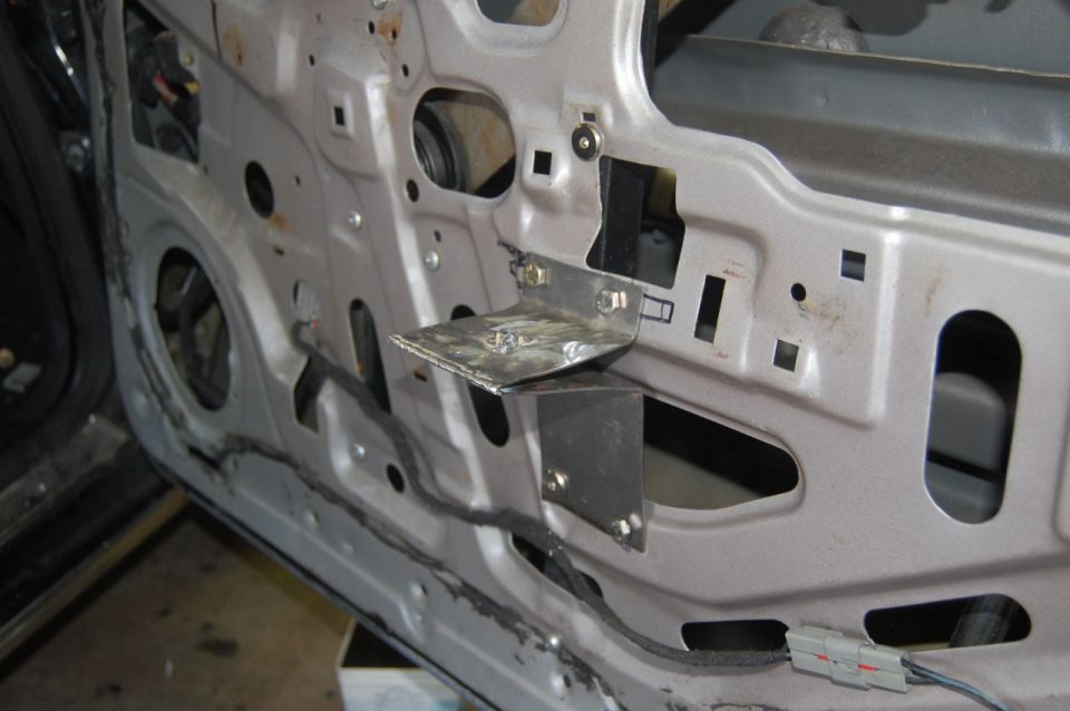 Custom metal bracket installed on the inside of a car door panel with wiring.