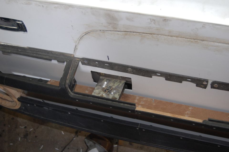 White vehicle rear bumper modification with visible metal bracket and wood support.