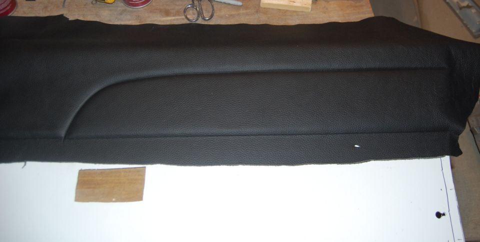 Black textured material with stitching and a curved seam