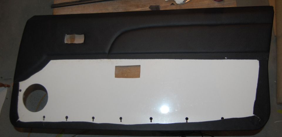Black automotive door panel with a white insert and speaker cutout.