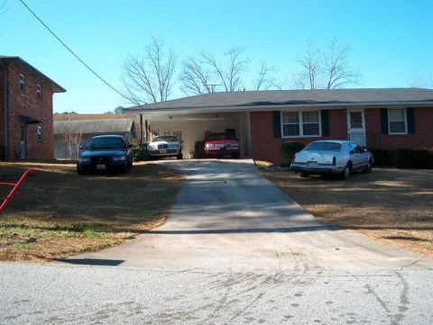 2001 Ford Crown Victoria - Several cars are parked in the driveway and yard of a suburban home under a clear blue sky.