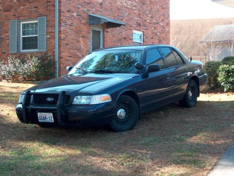 2001 Ford Crown Victoria - This 2001 Ford Crown Victoria, identified by its distinct body style and push bar, is seen from a three-quarter front view.