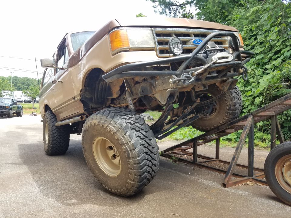Lifted 1988 Ford Bronco on ramps with custom bumper and winch.