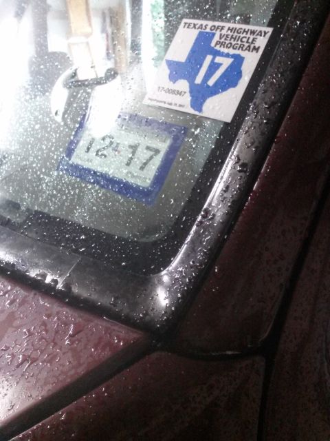 1996 Ford Bronco - A close-up view of a vehicle's windshield on a rainy day, showing two stickers and a digital gauge. One sticker is a Texas Off Highway Vehi…