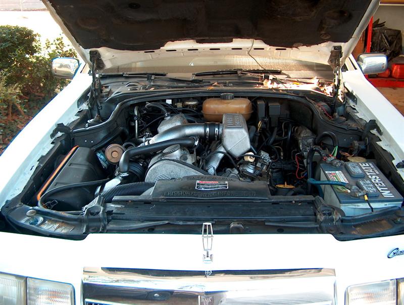 White car engine bay with hood open. Interstate battery visible