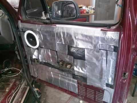 1996 Ford Bronco - The interior of a maroon vehicle door is shown, modified with sound-dampening material and a visible speaker. The door panel has been cover…