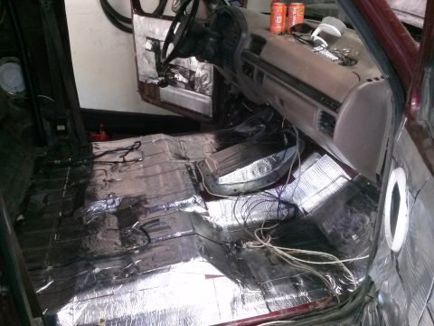 1996 Ford Bronco - The interior of a vehicle is shown with the floor covered in sound deadening material. Wires are visible running across the floor and up th…