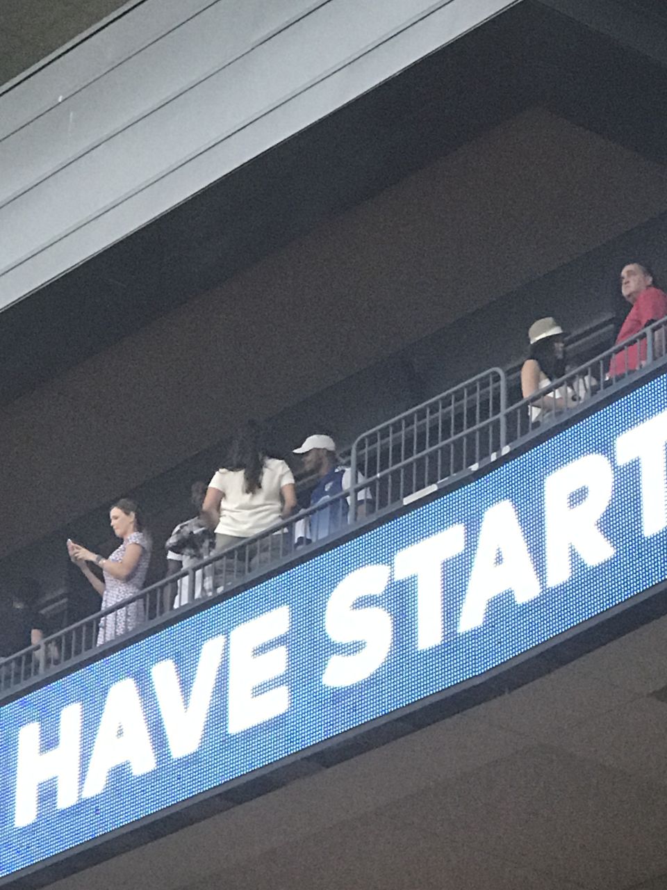 People on a balcony overlooking a large LED screen displaying "HAVE START".