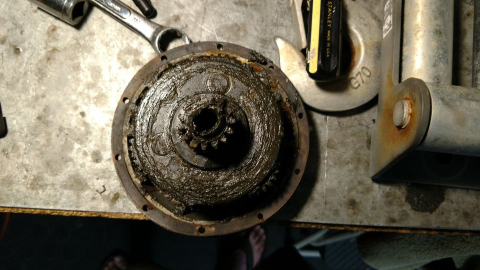 Greasy gear assembly with splined shaft and tools on a workbench.