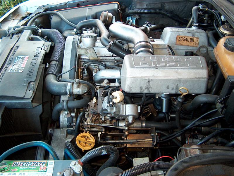 Engine bay with "TURBO DIESEL" cover and Interstate Megatron battery