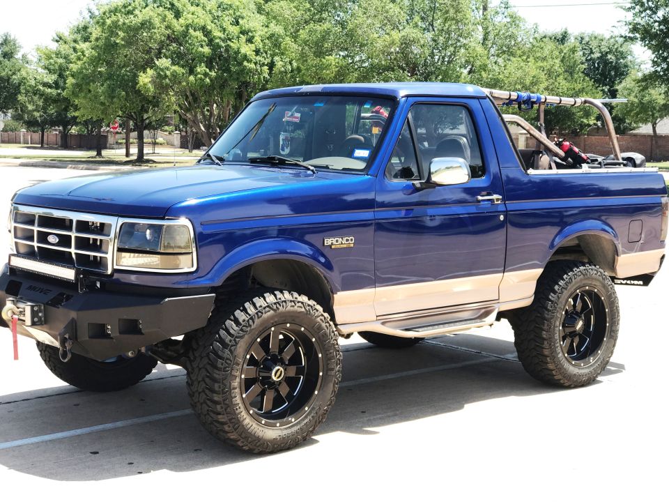 Blue 1996 Ford Bronco with tan accents, off-road tires, and custom bumper.