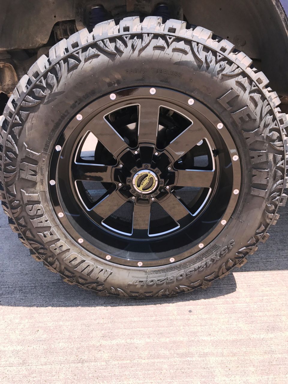 Black off-road tire with aggressive tread and white lettering on a black wheel.
