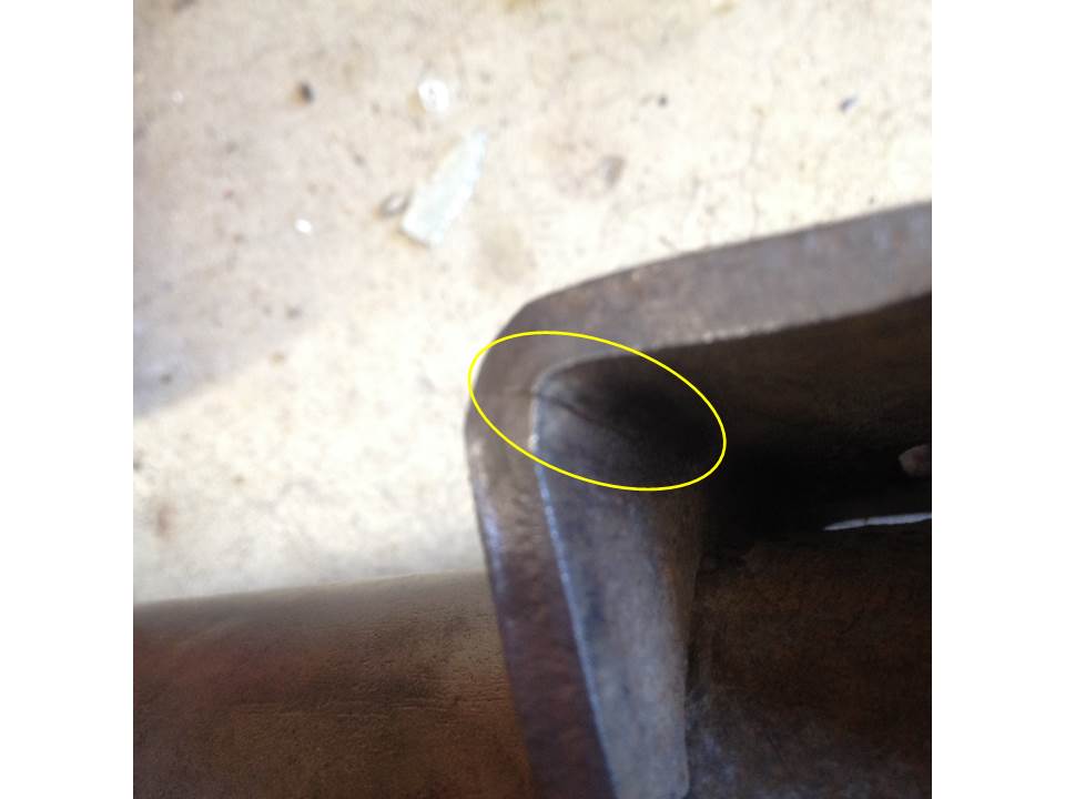 Close-up of a dark metal part with a rounded corner highlighted by a yellow circle.
