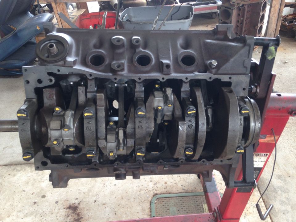 V8 engine block on a red engine stand, showing crankshaft and connecting rods.