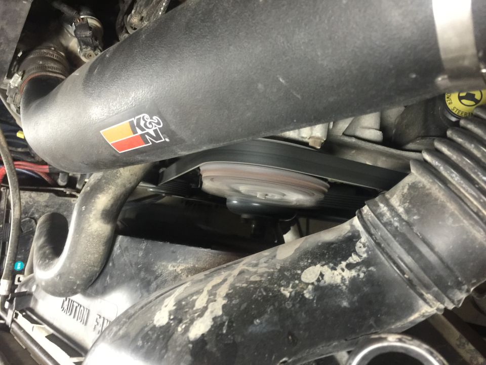 K&N intake tube and serpentine belt in a dirty engine bay.