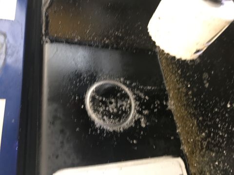 1996 Ford Bronco - A close-up view shows a circular metal cutout on a black surface, possibly a vehicle floor pan. A white pipe is angled above, with a stream…