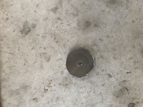 1996 Ford Bronco - A metal disc with a hole in the center is embedded in a concrete surface.