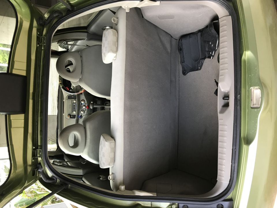 Interior view of a green 2003 Nissan Micra with rear seats folded down.