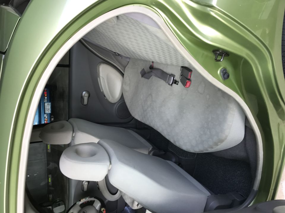 Interior of a green 2003 Nissan Micra showing rear seats and door panel.