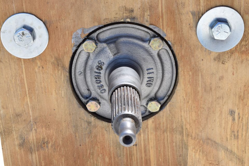 Splined shaft protruding from a metal hub assembly with part numbers 8976020 and GM 11, bolted to wood.