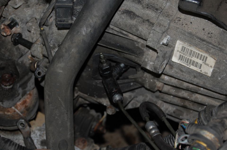 Close-up of a vehicle's engine bay showing a clutch slave cylinder and a large rubber hose.