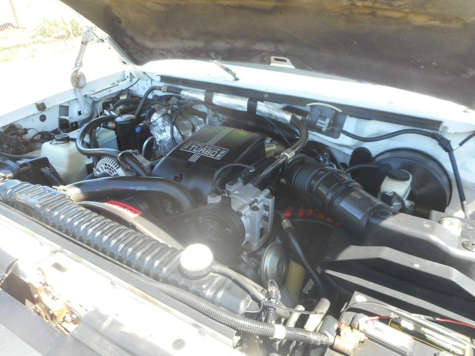 Engine bay of a white Ford F-250 pickup truck with hood open.
