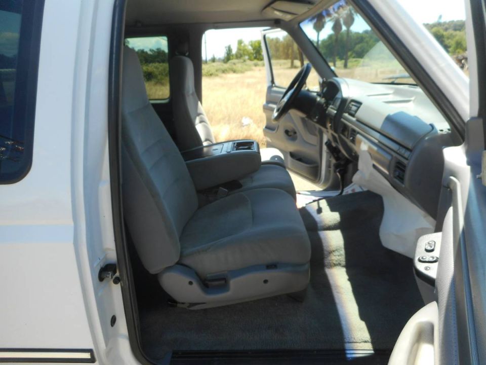 Interior of a white pickup truck, showing grey seats and dashboard.