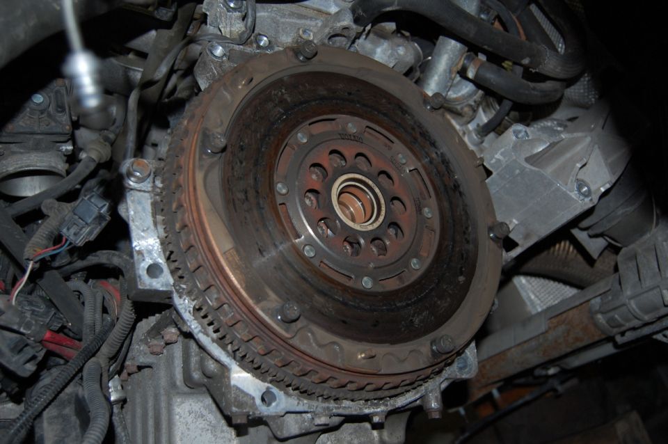 Vehicle flywheel and starter ring gear with engine components and wiring.