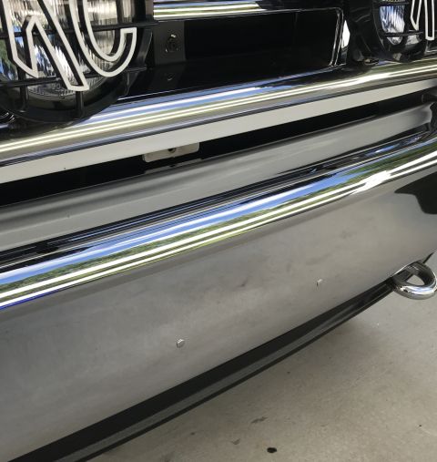1995 Ford Bronco - A close-up, low-angle shot of the chrome bumper and grille of a vehicle, possibly a 1995 Ford Bronco. The chrome reflects the sky and surro…