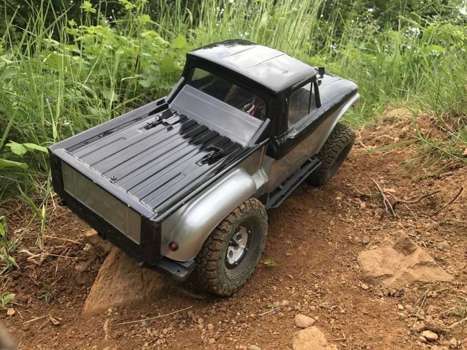 RC truck with silver body and black roof on dirt path