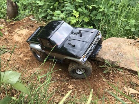 1989 Ford Bronco - A toy truck navigates a rocky, dirt path surrounded by greenery.