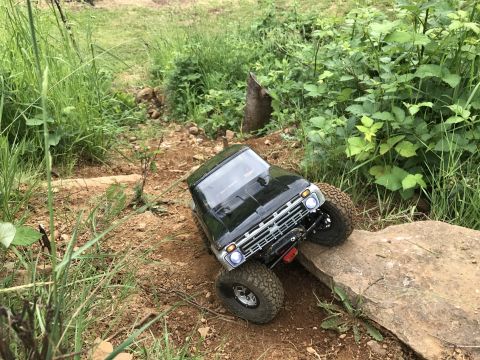 1989 Ford Bronco - This remote-controlled truck is navigating an obstacle course on a dirt trail surrounded by greenery.