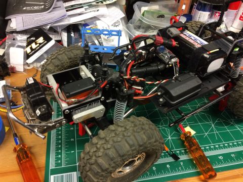 1989 Ford Bronco - RC crawler chassis with electronics and suspension parts laid out on a green cutting mat.