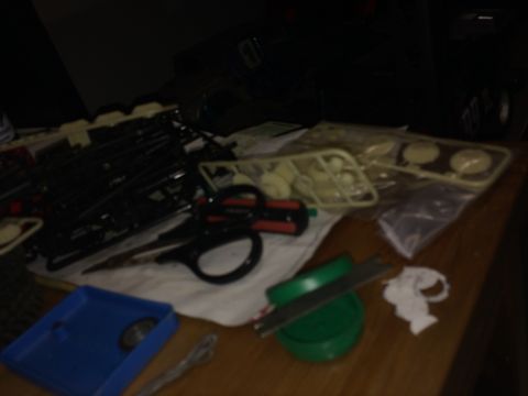 1989 Ford Bronco - Model car parts and hobby tools are laid out on a wooden table.