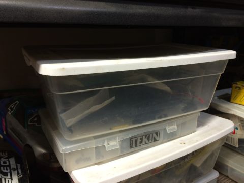 1989 Ford Bronco - RC car body stored in plastic containers on a shelf. Tekin logo on lower container.
