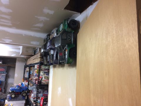 1989 Ford Bronco - Multiple RC car bodies are stored on a shelf, with some showing racing numbers and sponsor decals.