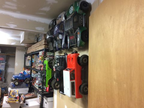 1989 Ford Bronco - Collection of RC car bodies displayed vertically on a wall, with storage shelves visible.