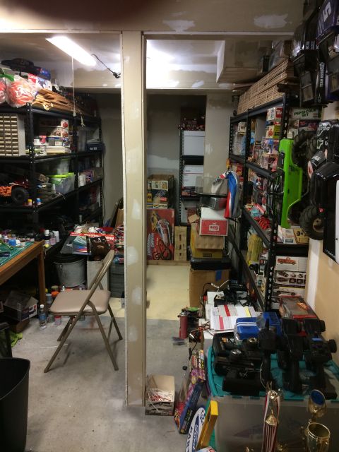 1989 Ford Bronco - A cluttered storage room contains shelves packed with RC car parts and accessories.