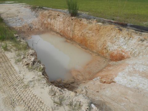 1992 Ford Bronco - Tire tracks are visible in the sand beside a ditch containing muddy water.