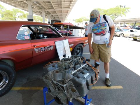 1968 Mercury Cougar - A man looks at a V8 engine displayed next to a classic 1968 Mercury Cougar at an outdoor event.