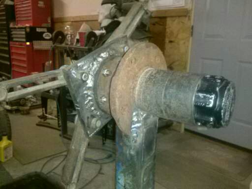 Custom suspension or axle assembly with welded metal and a black hub cap.