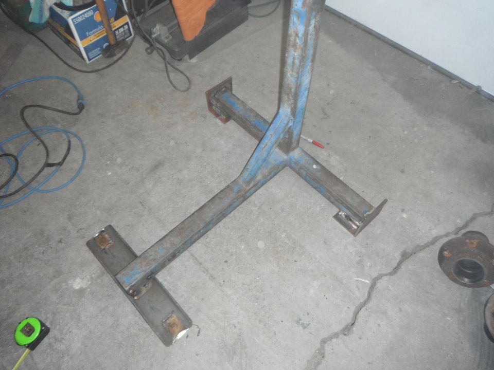 Blue metal stand base with welding, wires, and a box in a garage.
