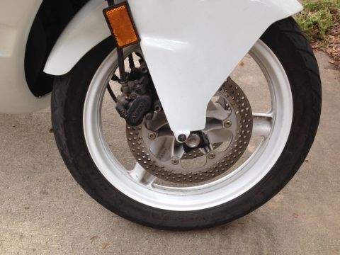 1989 Honda CBR600F - Close-up of the front wheel assembly of a white 1989 Honda CBR600F motorcycle.