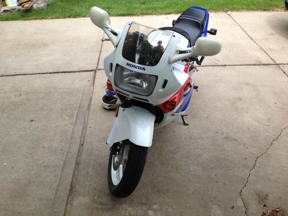 Front view of a white, red, and blue 1989 Honda CBR600F motorcycle parked on a concrete driveway